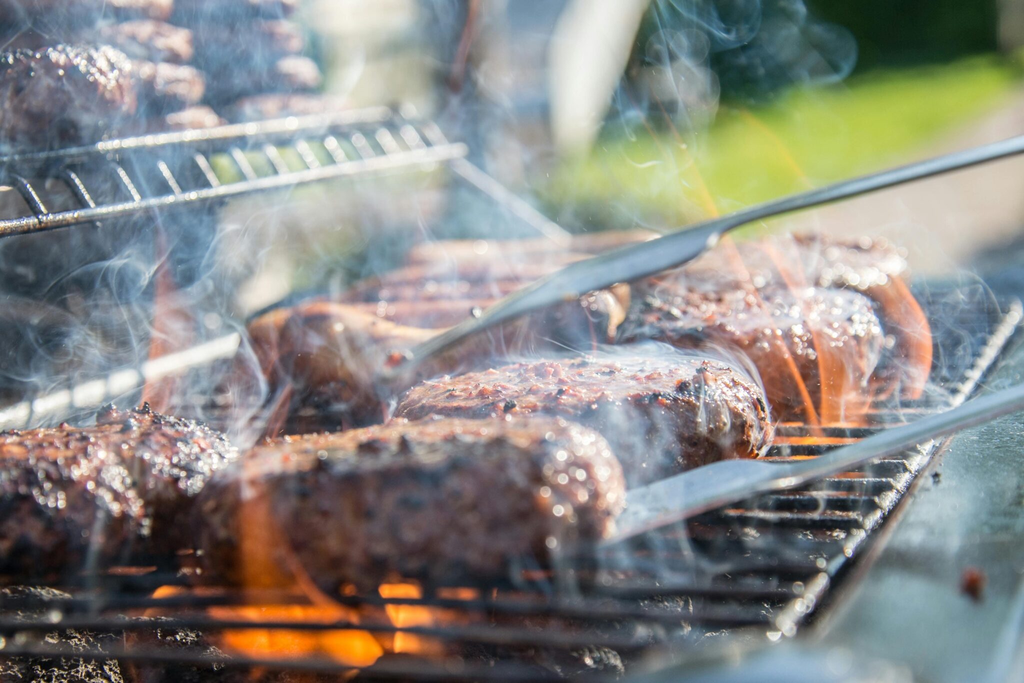 Gezin geniet van een perfecte BBQ met grilled vlees, salade en bijgerechten buiten aan tafel